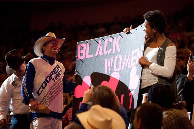 PBR head entertainer Flint Rasmussen awards the fan of day to a spectator who had a sign that read "Black women [heart] Flint"